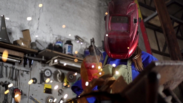 Welder Girl in Uniform in the Garage Working with Welding Equipment alt