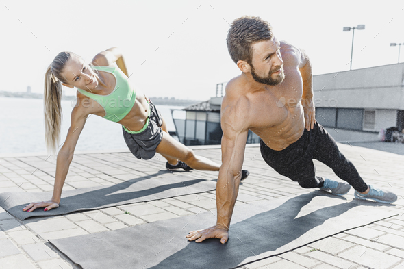 Fit fitness woman and man doing fitness exercises outdoors at city - Stock Photo - Images