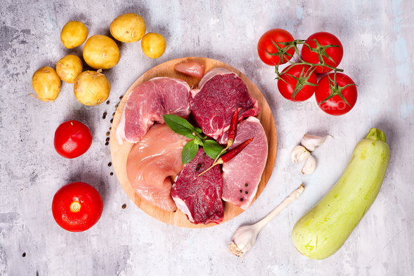 Selection of different raw meat with vegetables at wooden board .Lean proteins. - Stock Photo - Images
