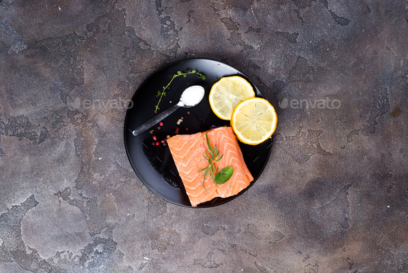 Salmon steaks on ice with lemon and salt on black plate. Lean proteins. - Stock Photo - Images