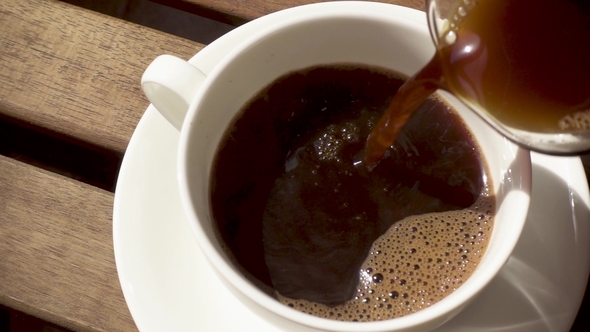 White Porcelain Cup on a Saucer on a Wooden Table with a Hot Drink