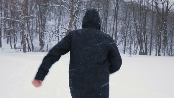 Man in Black Hood and Stylish Boots Running in Snowy Central Park, Snowfall