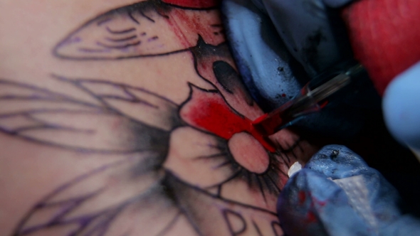 Tattoo Artist Doing a Tattoo in Studio alt