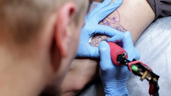Tattoo Artist Doing a Tattoo in Studio alt