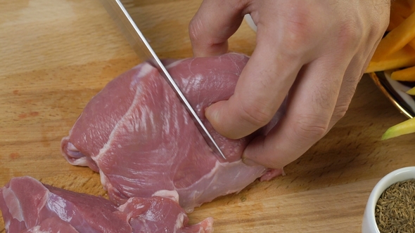 Chef Cutting the Raw Meat on a Wooden Board