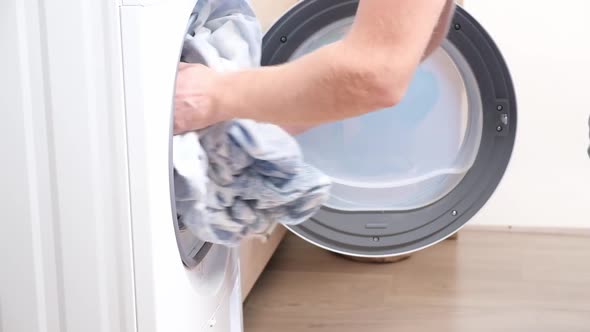 A Man Takes Dried Bed Linen Out of Dryer