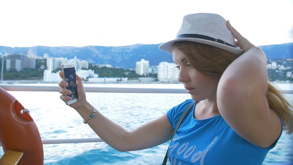 Woman in Hat Makes Selfie Bay with Yachts. Background Is the Town of Cremea