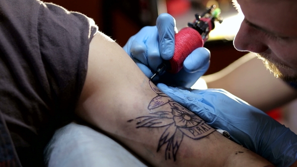 of Tattoo Artist Doing a Tattoo in Studio alt
