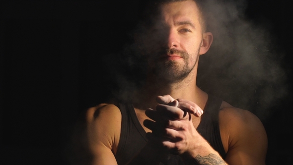 Strong Muscular Bearded Bodybuilder Clapping Hands with Chalk Powder Before Training