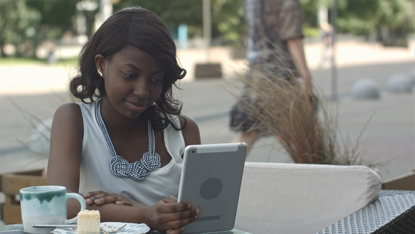 African American Woman Have Video Conferance on Her Tablet Sitting in Outside Cafe alt