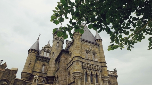 Huge Gothic Building in Summer Day, Camera Moves Through Branches of Tree