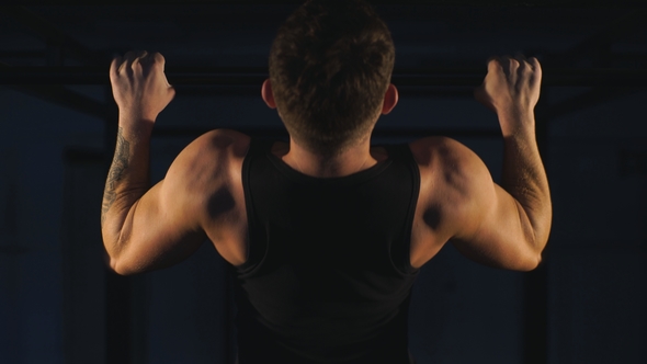 Muscular Back of Young Bodybuilder Training in Dark Background