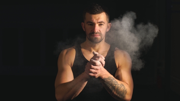 Male Athlete Comes Out of the Darkness and Clapping Hands with Chalk Powder