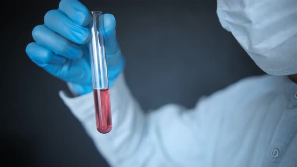 blue gloves demonstrates a test tube for collecting analysis with a red reagent (Stock Footage)