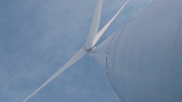 Wind Turbine Blades Rotate Against Blue Sky with Clouds