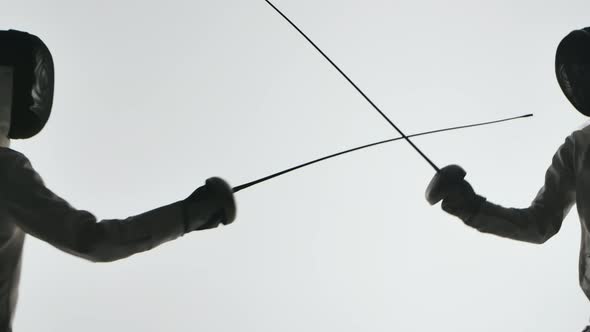 Two Fencers Are Fighting in a Tournament. Dark Silhouettes on White Background. Close Up. Slow alt