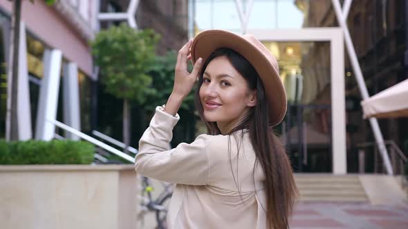 Happy Young Lady with Long Brown Hair Dressed in Beautiful Blouse and Stylish Hat Looking at Camera alt