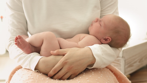 Happy Mother Lulls Her Newborn Baby in Her Arms alt