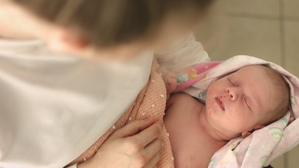 Sleeping Newborn Baby in the Arms of Mother in the Maternity Ward alt