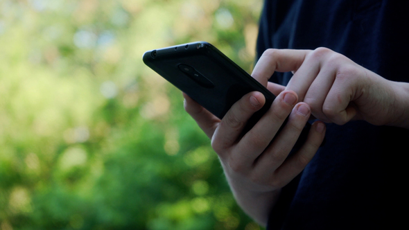 Small Hands of Child Holding Smartphone in Hands. Kid Playing Computer Games or Browsing Internet.