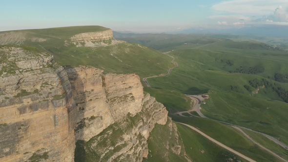 Flight Over a High Rock Cliff Revealing a View of the Pass in Russia alt