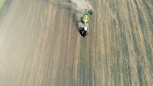 Planting Seeds With Tractor in springtime.Agricultural Planter on the Field alt