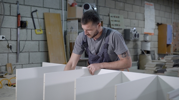Carpenter Carefully Getting Parts of a Shelf Together in a Workshop. alt
