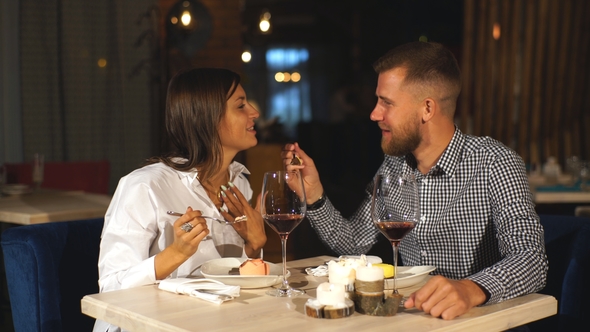 Young Couple on a Date. A Man Feeds His Woman a Delicious Dessert