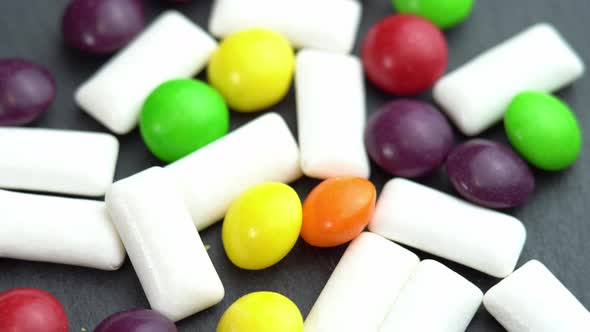 Sweets Colored Candies Skittles and Mint Chewing Pads Colored Sweets Rotate on a Black Plate alt