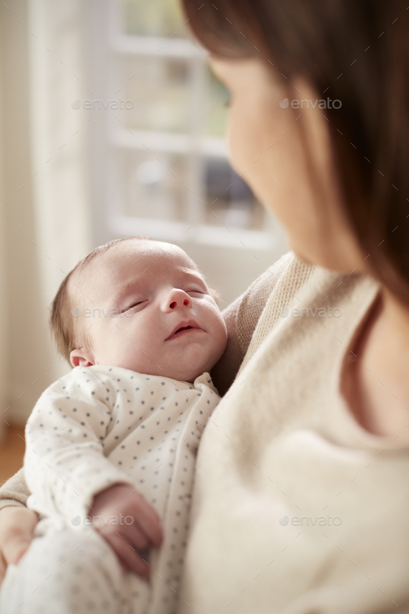 Close Up Of Sleeping Newborn Baby Being Held By Mother Stock Photo by