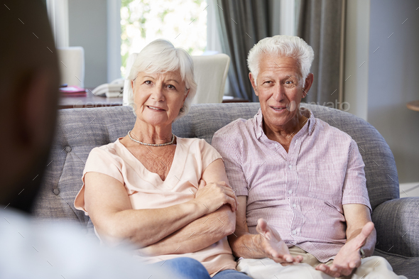 Happy senior couple taking financial advice at home Stock Photo by monkeybusiness