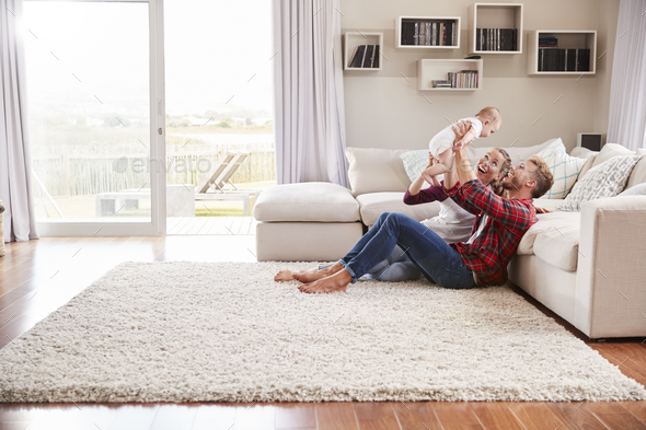 Young white couple play with their toddler in sitting room Stock Photo by monkeybusiness