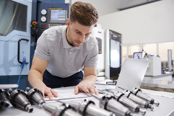 Male Engineer Measuring CAD Drawings In Factory Stock Photo by monkeybusiness