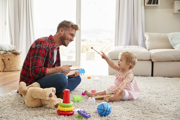 Father and young daughter playing toy instruments at home Stock Photo by monkeybusiness
