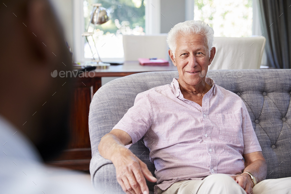 Happy senior man taking financial advice at home Stock Photo by monkeybusiness