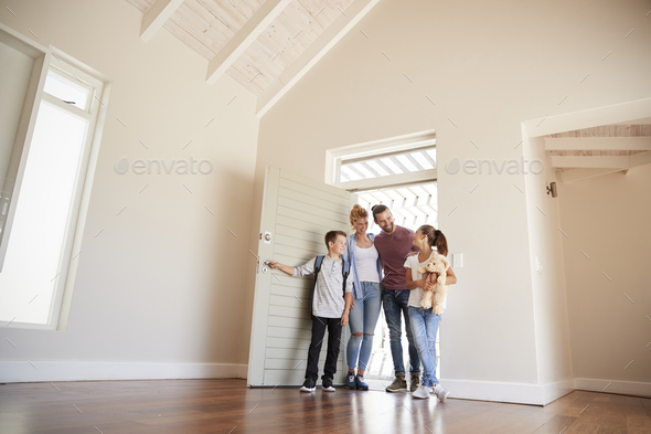 Family Opening Door And Walking In Empty Lounge Of New Home Stock Photo by monkeybusiness