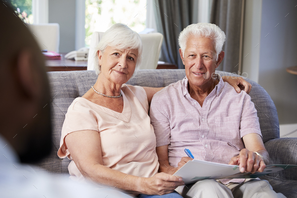 Happy senior couple taking financial advice at home Stock Photo by monkeybusiness