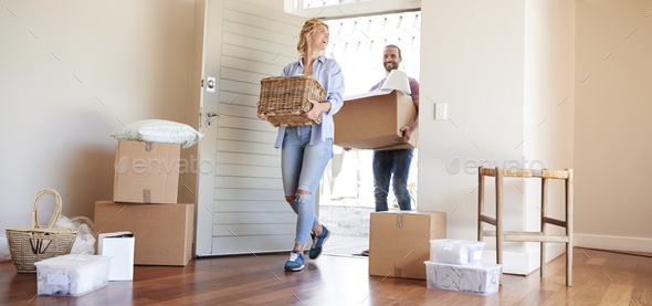 Couple Carrying Boxes Into New Home On Moving Day Stock Photo by monkeybusiness