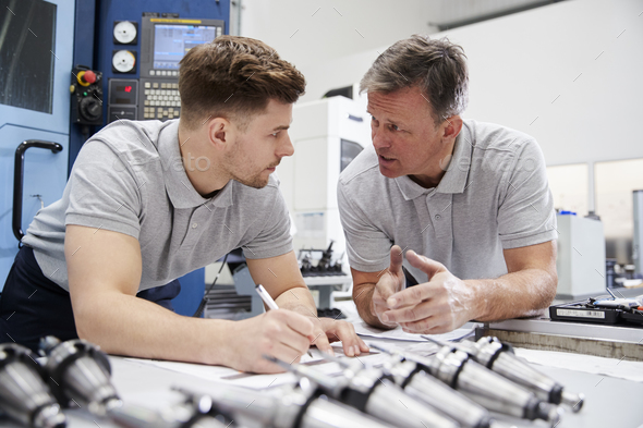 Engineer Showing Apprentice How To Measure CAD Drawings Stock Photo by monkeybusiness