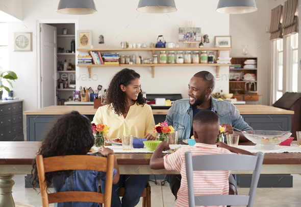 Black family of four having lunch in their kitchen at home Stock Photo by monkeybusiness