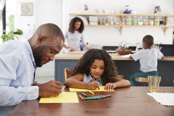 Young black family of four busy in their kitchen, close up Stock Photo by monkeybusiness
