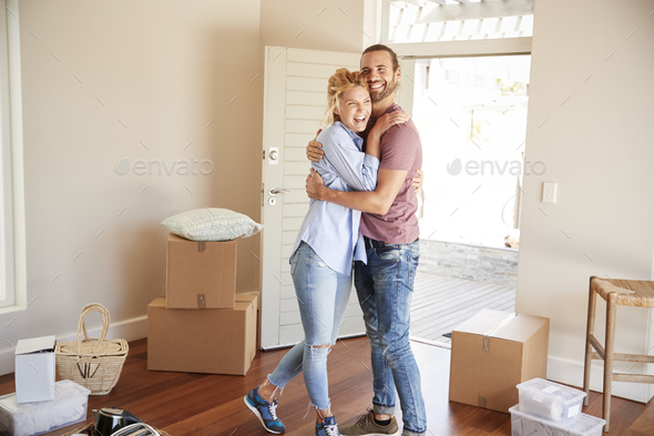 Happy Couple Surrounded By Boxes In New Home On Moving Day Stock Photo by monkeybusiness