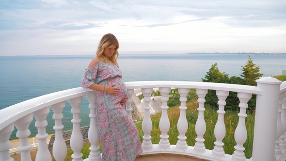 A Pregnant Girl Stands on the Balcony Next To the Sea and Caresses Her Tummy