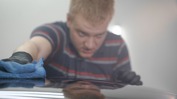 Worker Polishing Rooftop of a Car with Towel After Washing. alt