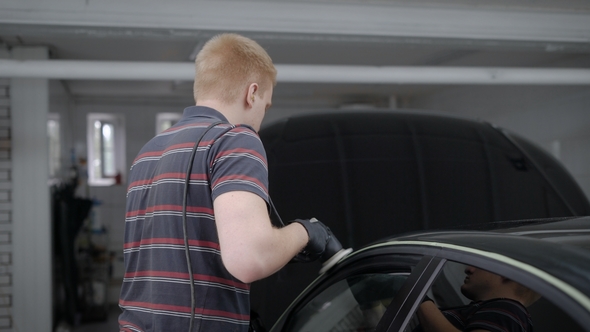 Male Worker Working on Polishing Machine on Carwash Station. alt