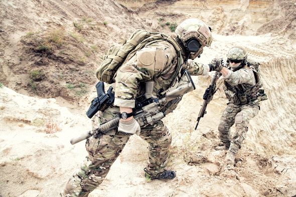 American commando helping friend to climb on dune - Stock Photo - Images