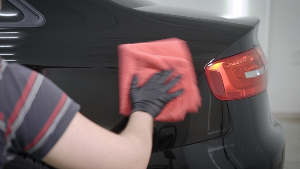 Master Is Polishing a Rear Part of Automobile By Red Soft Cloth in Auto Workshop After Washing alt