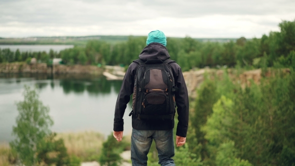 Portrait of Active Young Man Traveller with Knapsack Walking Down the Mountain  alt