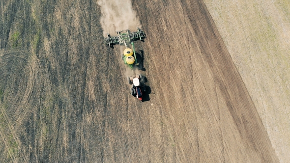Top View of a Plough Sowing a Massive Field and Raising Dust alt