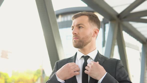 Businessman Adjusting Suit and Tie Near the Business Center alt